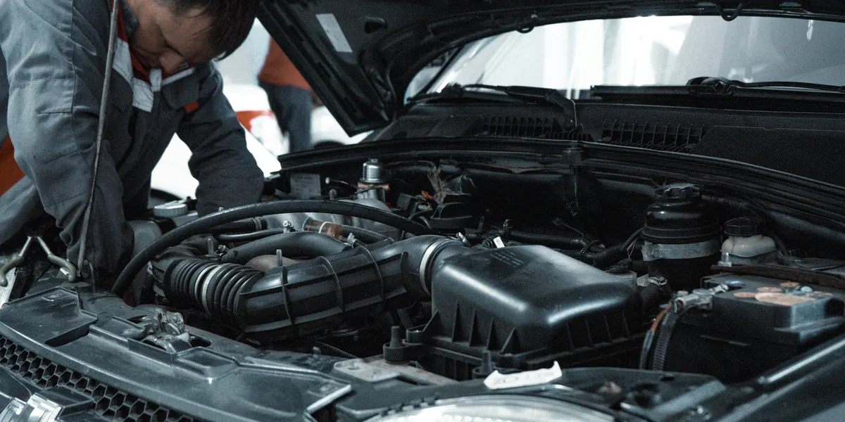 Motor kaputu açık bir aracı inceleyen kişi